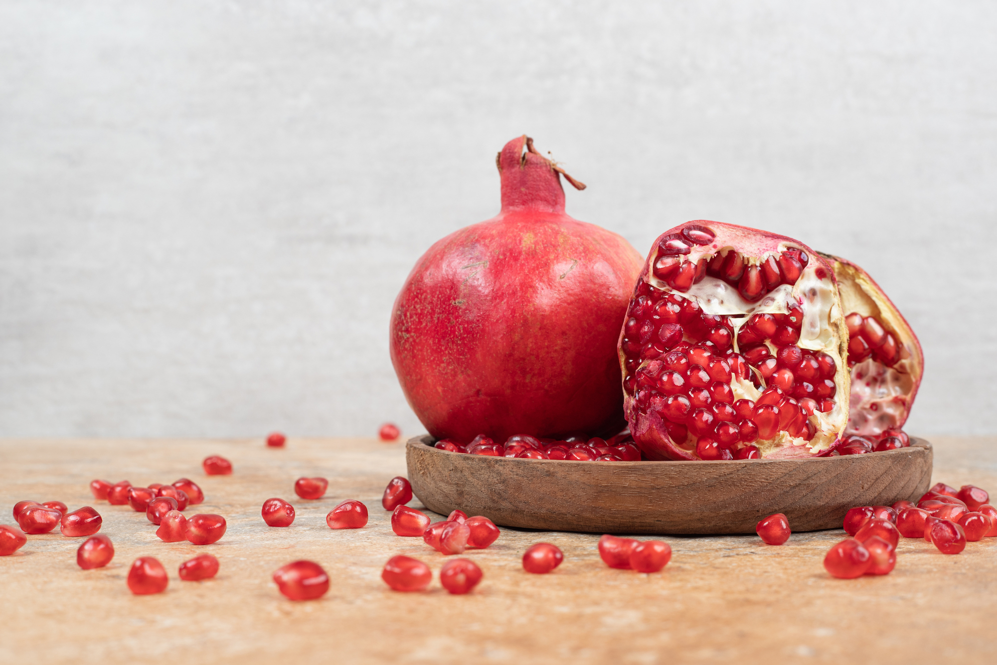 ripe-pomegranates-seeds-wooden-plate.jpg